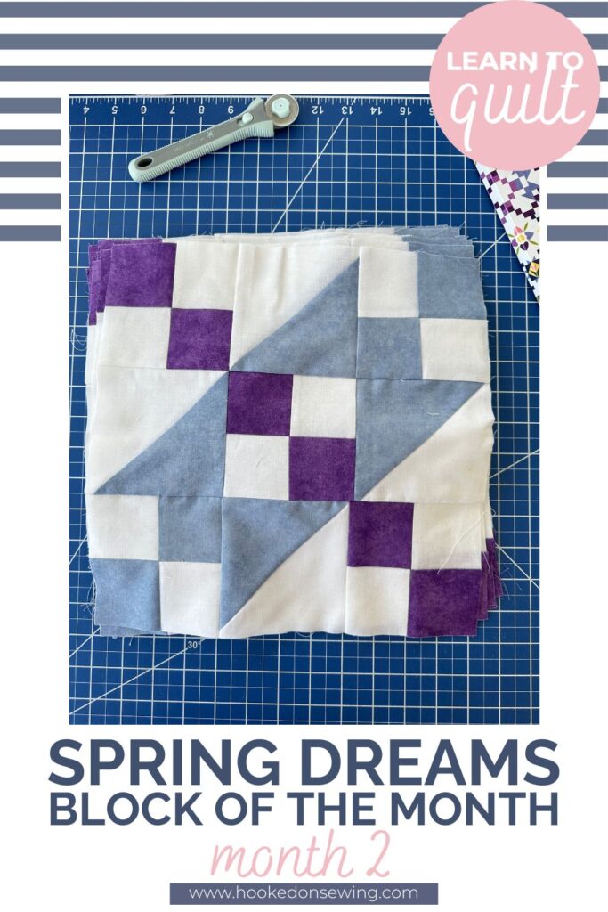 Jacob's Ladder Quilt block in blue, purple and white laying on a blue cutting mat by a 28mm rotary cutter